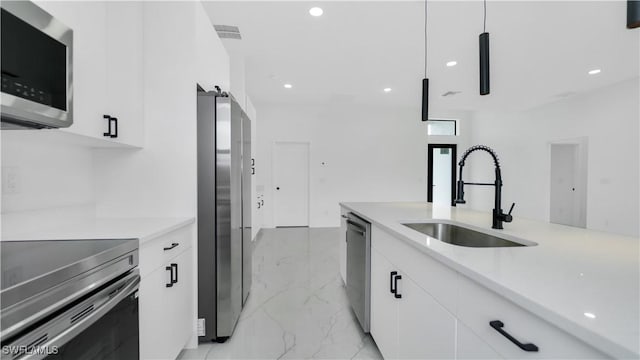 kitchen with a sink, stainless steel appliances, marble finish floor, and white cabinetry