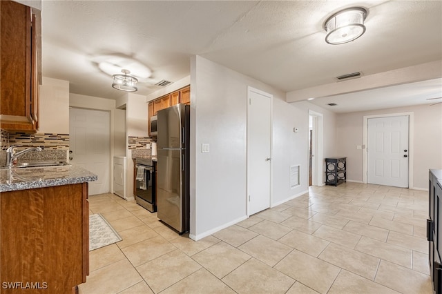 2184 Barry Dr, Fort Myers, FL 33907 - kitchen with tasteful backsplash, brown cabinets, appliances with stainless steel finishes, light tile patterned flooring, and a sink