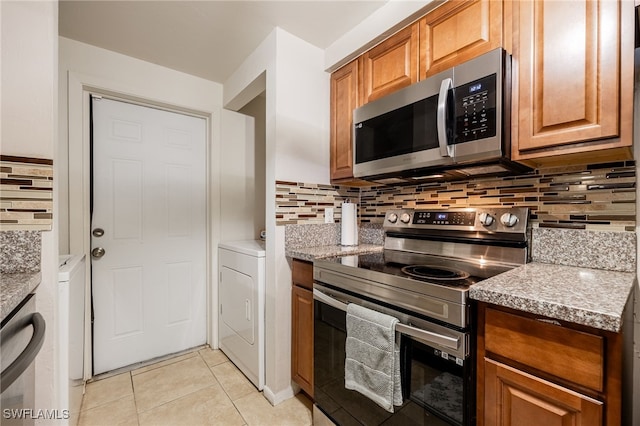 2184 Barry Dr, Fort Myers, FL 33907 - kitchen featuring stainless steel appliances, washer / clothes dryer, tasteful backsplash, and brown cabinets