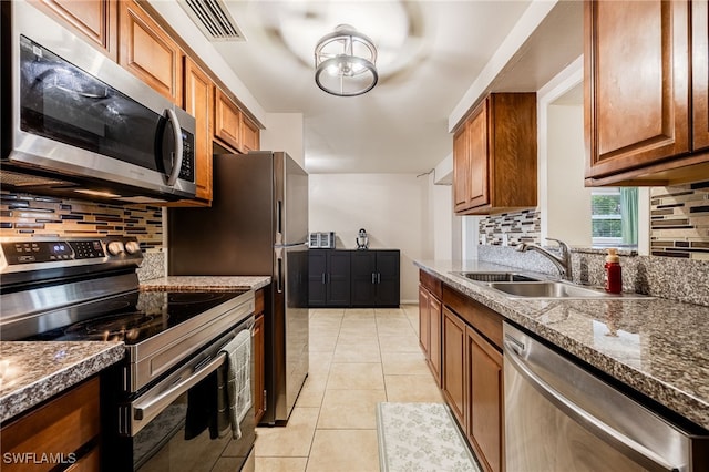 2184 Barry Dr, Fort Myers, FL 33907 - kitchen featuring a sink, brown cabinets, appliances with stainless steel finishes, and light tile patterned floors