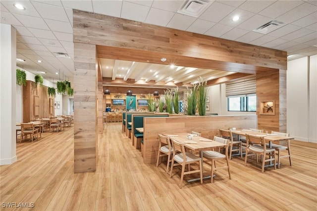 dining space with visible vents, wood finished floors, and wood walls