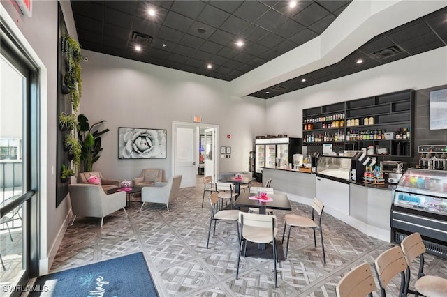 dining space with a high ceiling, baseboards, and visible vents