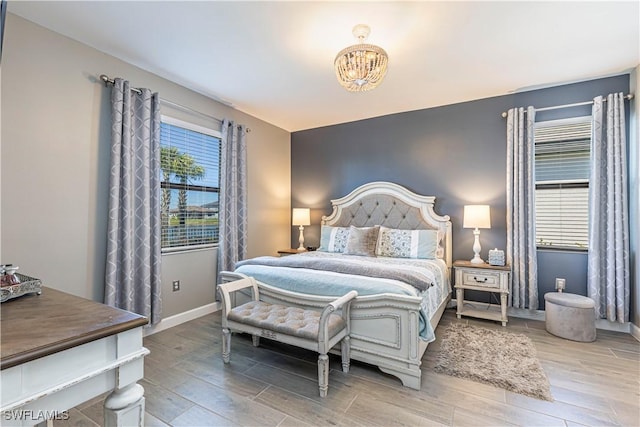 bedroom with baseboards, a notable chandelier, and wood finished floors