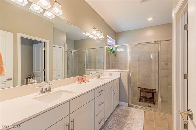 bathroom featuring a shower stall, wood finished floors, double vanity, and a sink