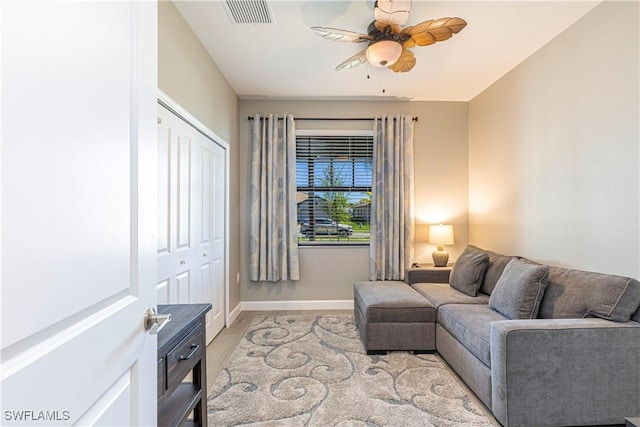 living area featuring visible vents, baseboards, a ceiling fan, and light wood finished floors