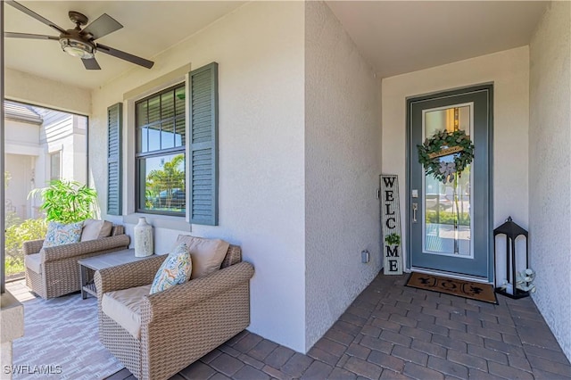 entrance to property featuring stucco siding, covered porch, and ceiling fan