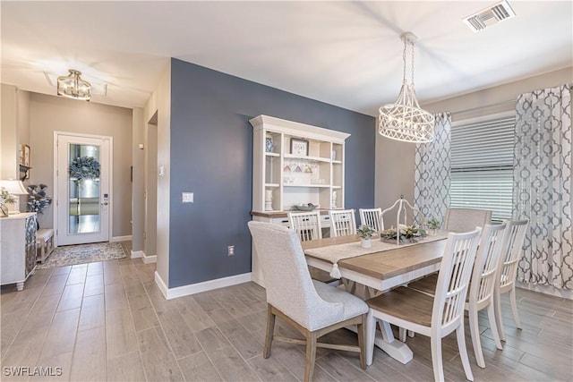 dining room featuring visible vents, wood finish floors, baseboards, and an inviting chandelier