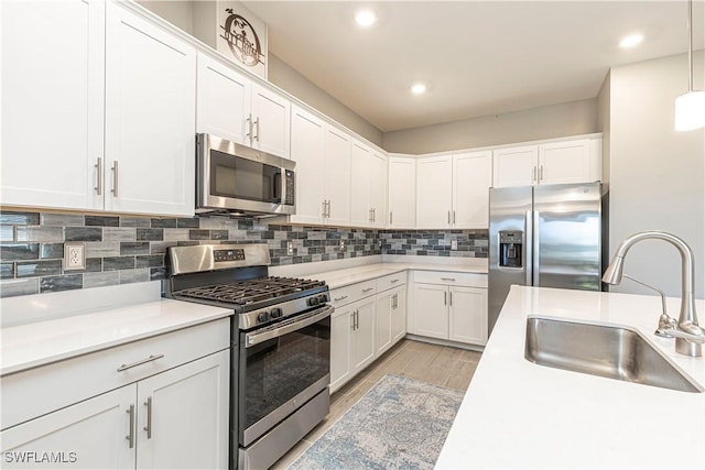 kitchen featuring tasteful backsplash, light countertops, appliances with stainless steel finishes, white cabinets, and a sink