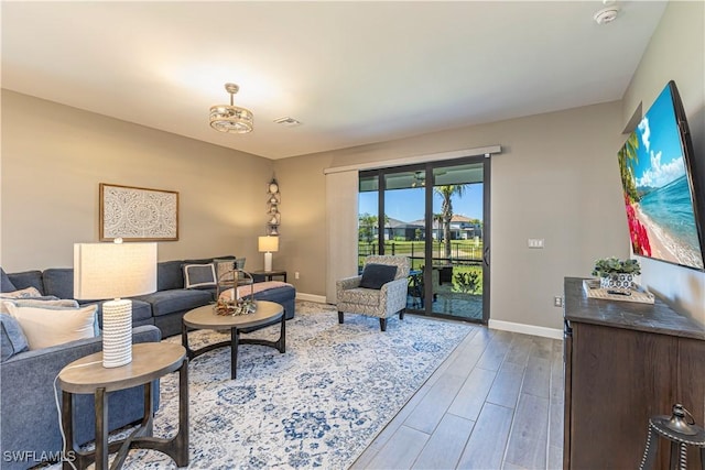 living area featuring visible vents, baseboards, and wood finished floors