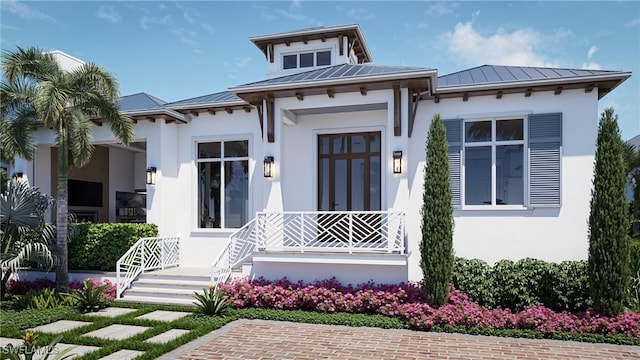 view of front facade with metal roof, covered porch, stucco siding, and a standing seam roof