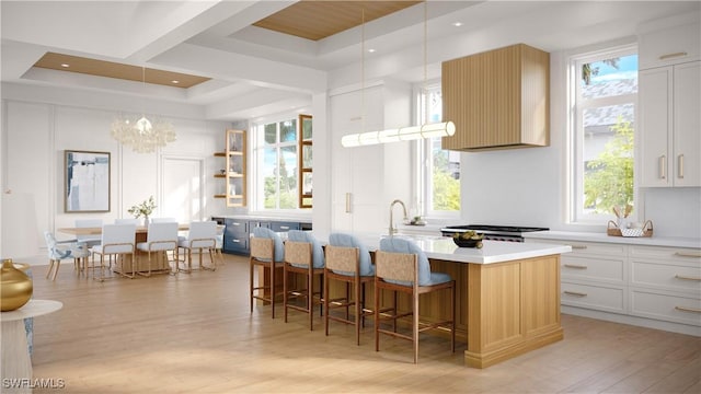 kitchen with an island with sink, a healthy amount of sunlight, light wood-type flooring, and a kitchen bar