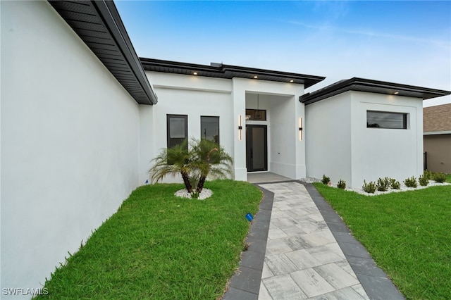 property entrance featuring stucco siding and a yard