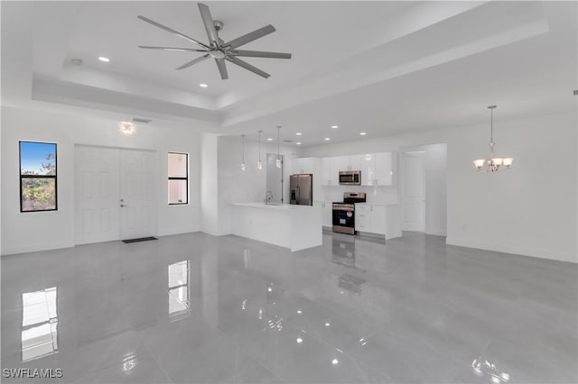 unfurnished living room featuring recessed lighting, ceiling fan with notable chandelier, a raised ceiling, and a sink