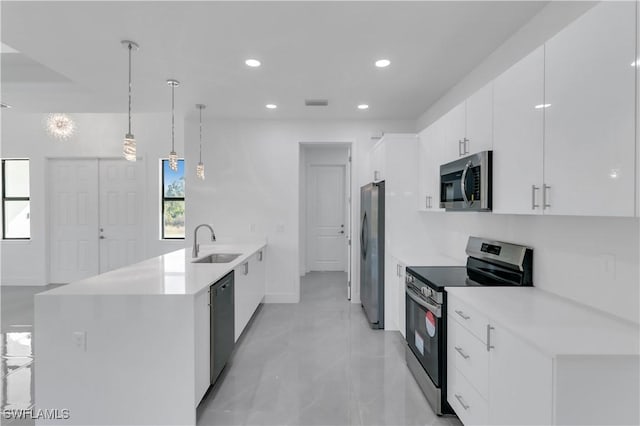 kitchen featuring light countertops, a peninsula, white cabinets, stainless steel appliances, and a sink