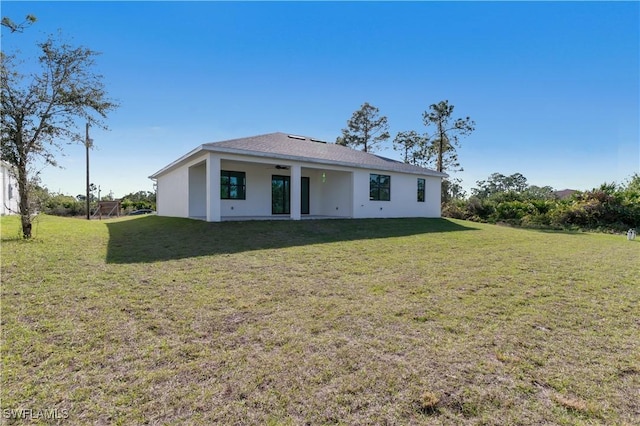 back of property featuring stucco siding, a yard, and ceiling fan