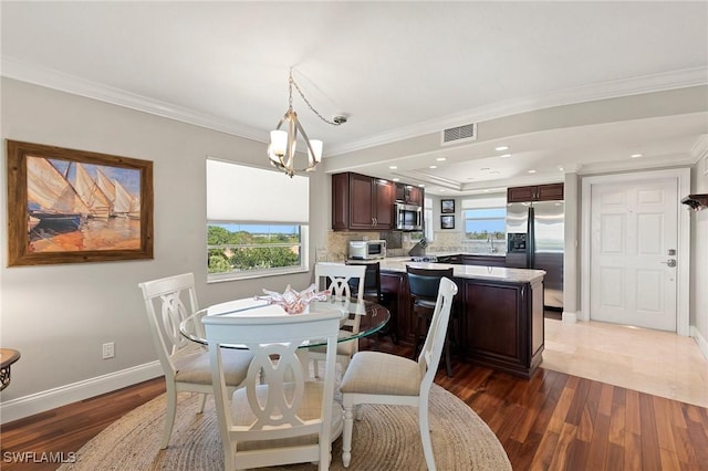 dining room featuring visible vents, baseboards, wood finished floors, and ornamental molding