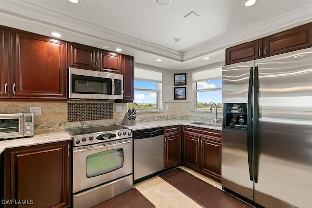 kitchen featuring a sink, a tray ceiling, appliances with stainless steel finishes, a toaster, and decorative backsplash