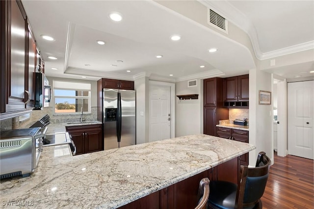 kitchen featuring visible vents, appliances with stainless steel finishes, a peninsula, and crown molding