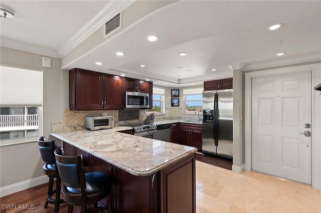 kitchen with visible vents, a sink, stainless steel appliances, a peninsula, and crown molding