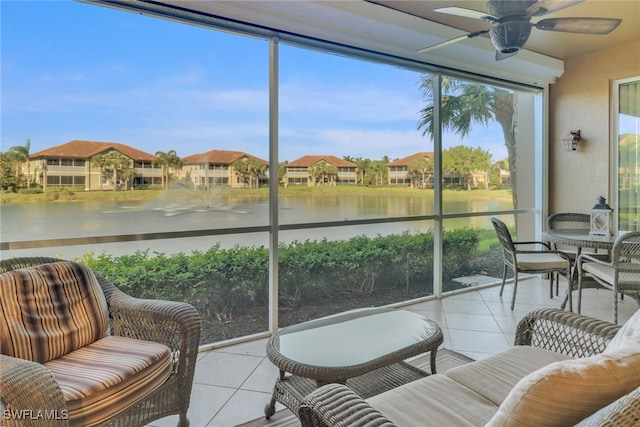 sunroom / solarium featuring a ceiling fan, tile patterned floors, and a water view