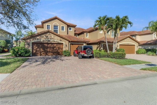 view of front of house featuring stucco siding, an attached garage, a tile roof, and decorative driveway