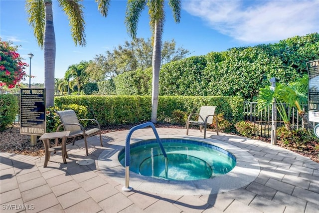view of pool featuring fence, a community hot tub, and a patio area