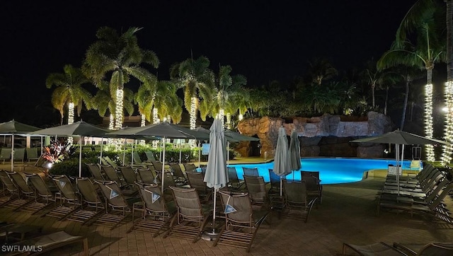 pool at night featuring a community pool