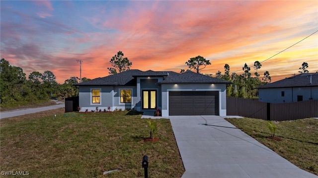 view of front of home with stucco siding, driveway, fence, a front yard, and an attached garage