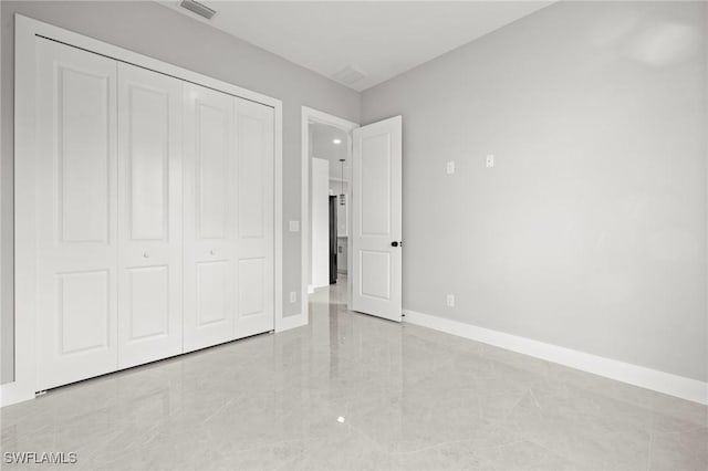 unfurnished bedroom featuring marble finish floor, baseboards, visible vents, and a closet