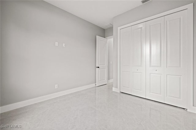 unfurnished bedroom with visible vents, baseboards, and a closet