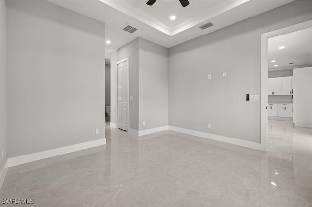 unfurnished room featuring a tray ceiling, baseboards, and visible vents