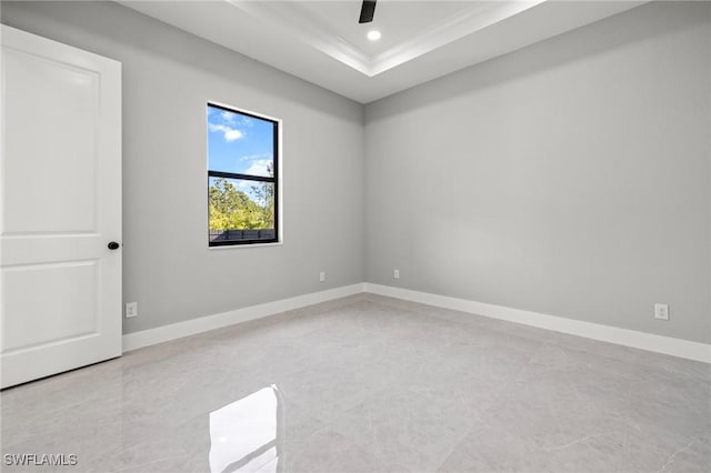 spare room featuring a raised ceiling, ornamental molding, a ceiling fan, recessed lighting, and baseboards