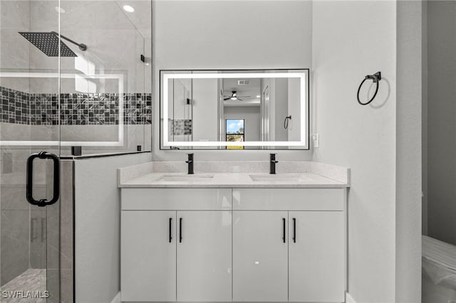 full bath featuring double vanity, a ceiling fan, a stall shower, and a sink