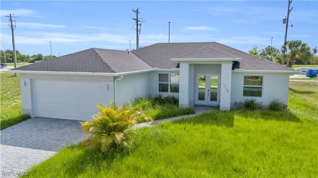 view of front facade with stucco siding, decorative driveway, french doors, roof with shingles, and a garage