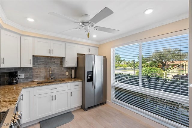 kitchen featuring light stone counters, ornamental molding, a sink, appliances with stainless steel finishes, and tasteful backsplash