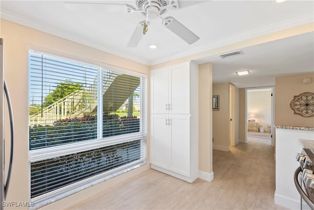 interior space featuring visible vents, light wood-style flooring, a ceiling fan, crown molding, and baseboards