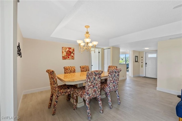 dining room with light wood finished floors, an inviting chandelier, and baseboards