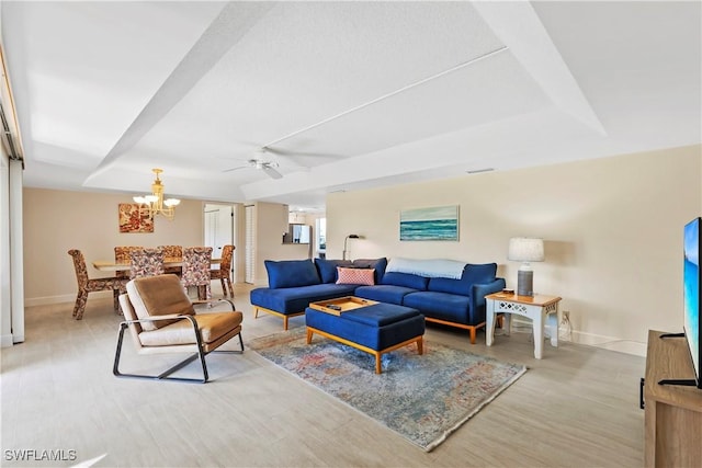 living room with baseboards, a raised ceiling, and light wood-style floors