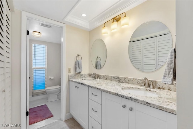 full bath with a sink, toilet, double vanity, and crown molding