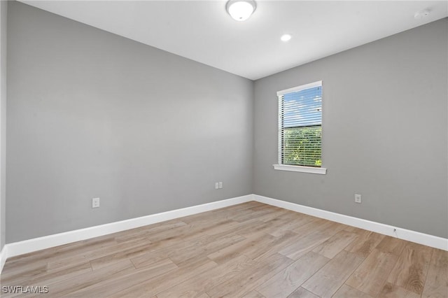 unfurnished room featuring baseboards and light wood finished floors