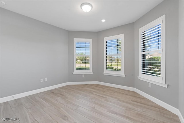 spare room with baseboards and light wood-type flooring