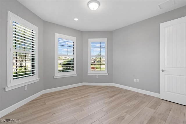 spare room with baseboards and light wood finished floors