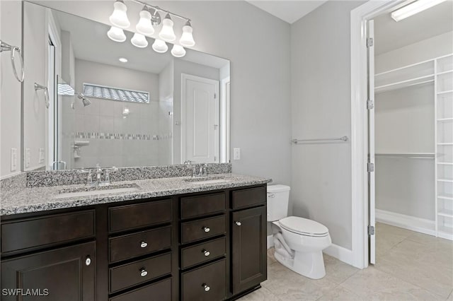 bathroom featuring double vanity, toilet, walk in shower, and a sink