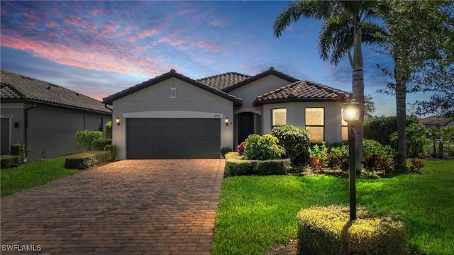 mediterranean / spanish-style house with decorative driveway, stucco siding, an attached garage, and a tile roof