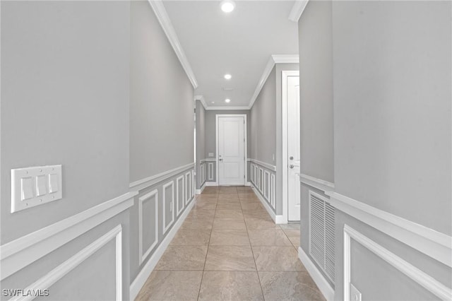 hall featuring a decorative wall, ornamental molding, recessed lighting, and wainscoting