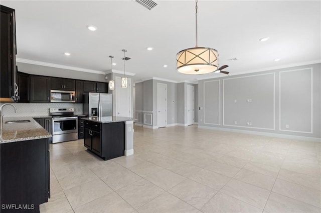 kitchen featuring visible vents, a sink, stainless steel appliances, a decorative wall, and decorative backsplash