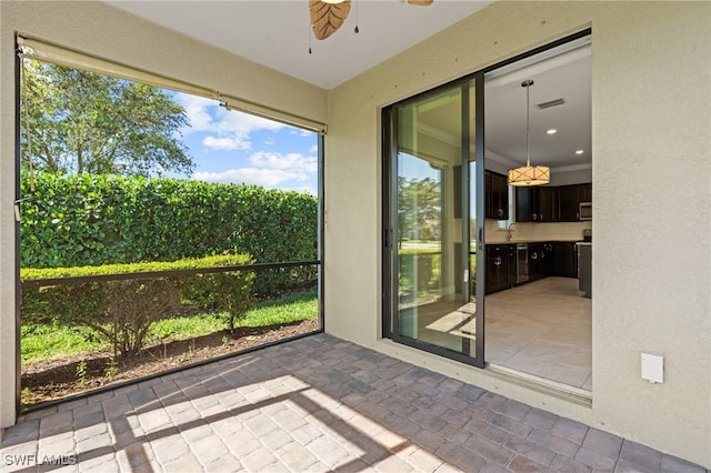 unfurnished sunroom with visible vents, a ceiling fan, and a sink