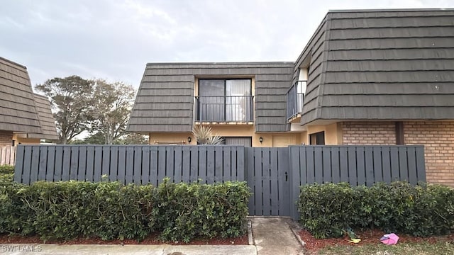 view of side of home with mansard roof and brick siding