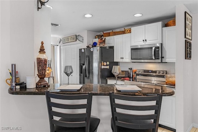 3319 Surfside Blvd, Cape Coral, FL 33914 - kitchen with backsplash, white cabinets, appliances with stainless steel finishes, and a breakfast bar area