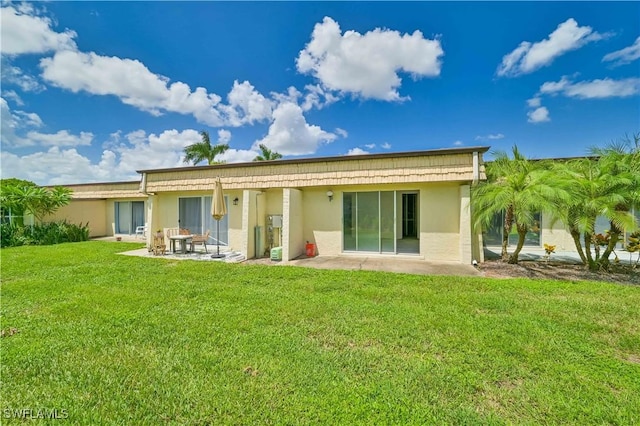 back of property with stucco siding, a patio, and a lawn